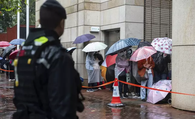 People wait to enter the West Kowloon Magistrates' Courts in Hong Kong, Wednesday, Nov. 20, 2024, ahead of Hong Kong activist publisher Jimmy Lai's national security trial. (AP Photo/Chan Long Hei)