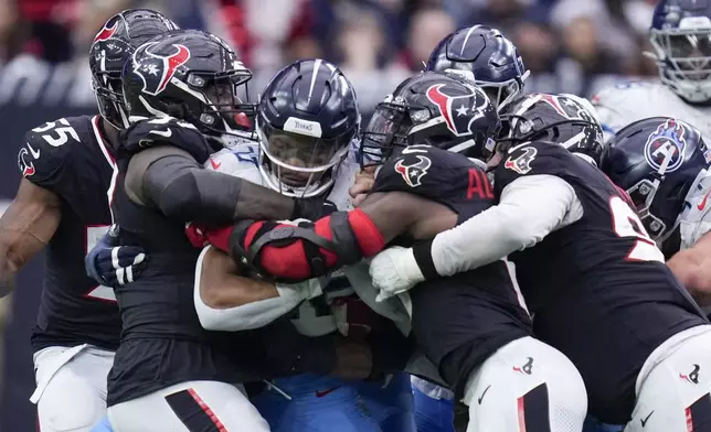 Tennessee Titans running back Tony Pollard, center, is tackled the Houston Texans defense during the second half an NFL football game Sunday, Nov. 24, 2024, in Houston. (AP Photo/Eric Christian Smith)