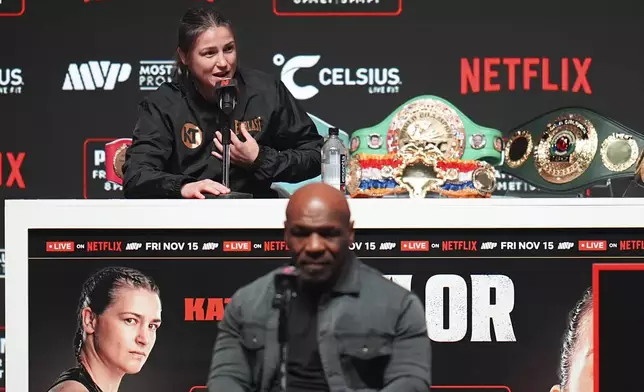 Mike Tyson, bottom, listens as Katie Taylor speaks during a news conference ahead of her undisputed super lightweight world title bout against Amanda Serrano, the co-main event in the Tyson vs. Jake Paul fight night, Wednesday, Nov. 13, 2024, in Irving, Texas. (AP Photo/Julio Cortez)