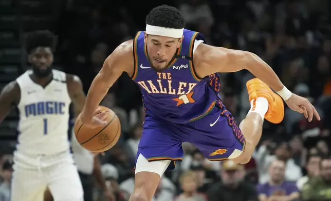 Phoenix Suns guard Devin Booker, right, dives in vain to save the ball on a backcourt violation as Orlando Magic forward Jonathan Isaac (1) looks on during the first half of an NBA basketball game Monday, Nov. 18, 2024, in Phoenix. (AP Photo/Ross D. Franklin)