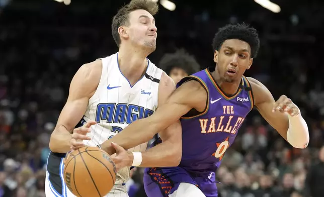 Phoenix Suns forward Ryan Dunn (0) fouls Orlando Magic forward Franz Wagner, left, during the first half of an NBA basketball game Monday, Nov. 18, 2024, in Phoenix. (AP Photo/Ross D. Franklin)