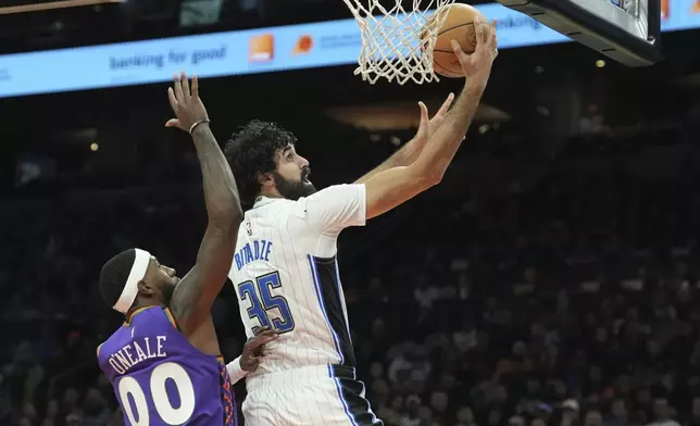 Orlando Magic center Goga Bitadze (35) drives past Phoenix Suns forward Royce O'Neale (00) during the first half of an NBA basketball game Monday, Nov. 18, 2024, in Phoenix. (AP Photo/Ross D. Franklin)