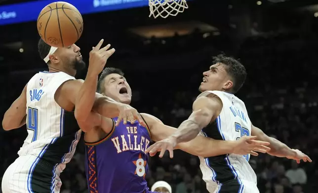 Phoenix Suns guard Grayson Allen (8) is fouled by Orlando Magic guard Jalen Suggs (4) as Magic forward Tristan da Silva, right, defends during the second half of an NBA basketball game Monday, Nov. 18, 2024, in Phoenix. (AP Photo/Ross D. Franklin)