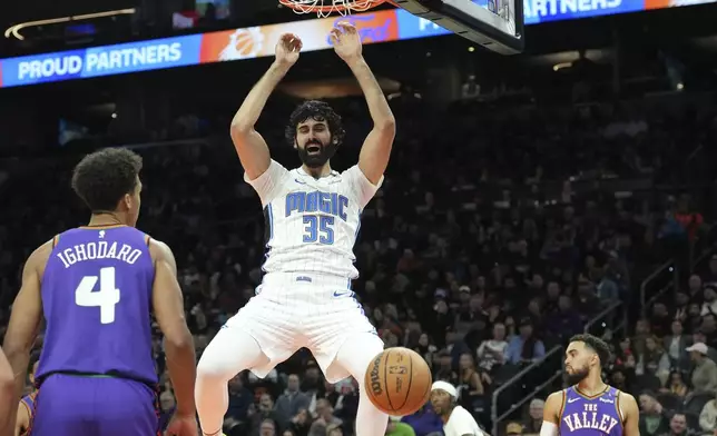 Orlando Magic center Goga Bitadze (35) dunks as Phoenix Suns center Oso Ighodaro (4) and guard Tyus Jones (21) look on during the first half of an NBA basketball game Monday, Nov. 18, 2024, in Phoenix. (AP Photo/Ross D. Franklin)