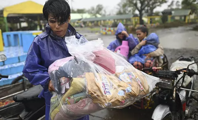 A man carries belongings as they evacuate to safer grounds in Santa Ana, Cagayan province, northern Philippines as Typhoon Usagi approaches Thursday Nov. 14, 2024. (AP Photo/Noel Celis)