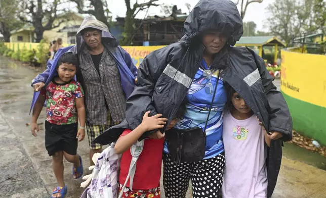 Residents use jackets to protect them from rain as they evacuate their homes in Santa Ana, Cagayan province, northern Philippines as Typhoon Usagi approaches Thursday, Nov. 14, 2024. (AP Photo/Noel Celis)