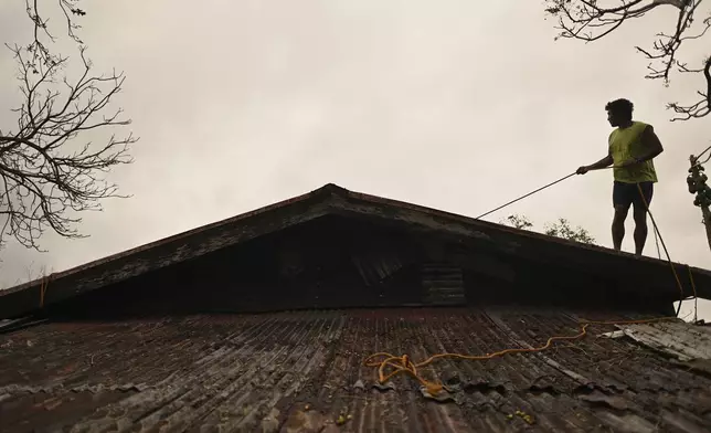 A resident reinforces the roof of their house in Santa Ana, Cagayan Province, northern Philippines as they anticipate Typhoon Usagi to hit their area Thursday, Nov. 14, 2024. (AP Photo/Noel Celis)