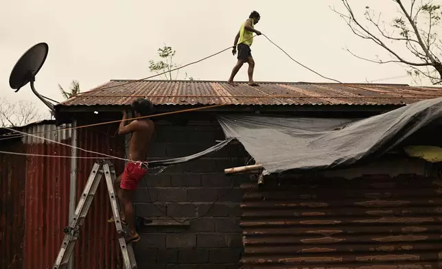 A resident reinforces his roof in Santa Ana, Cagayan Province, northern Philippines as they anticipate Typhoon Usagi to hit their area Thursday, Nov. 14, 2024. (AP Photo/Noel Celis)