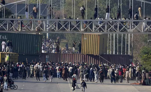 Supporters of imprisoned former premier Imran Khan's Pakistan Tehreek-e-Insaf party, gather to remove shipping container to clear way for their rally demanding Khan's release, in Islamabad, Pakistan, Tuesday, Nov. 26, 2024. (AP Photo/Anjum Naveed)