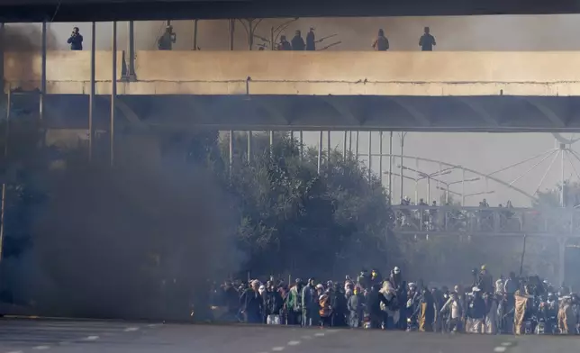 Supporters of imprisoned former Premier Imran Khan's Pakistan Tehreek-e-Insaf party move forwards following police fire tear gas shells to disperse them during clashes in Islamabad, Pakistan, Tuesday, Nov. 26, 2024. (AP Photo/Anjum Naveed)