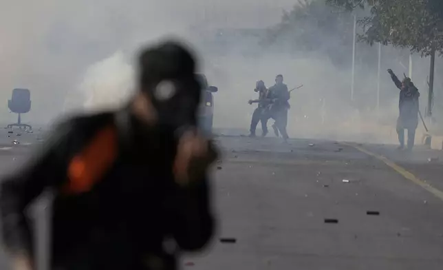 Supporters of imprisoned former premier Imran Khan’s Pakistan Tehreek-e-Insaf party, throw stone as police fire tear gas shell to disperse them during clashes, in Islamabad, Pakistan, Tuesday, Nov. 26, 2024. (AP Photo/Anjum Naveed)