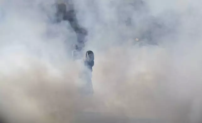 A supporter of imprisoned former premier Imran Khan's Pakistan Tehreek-e-Insaf party, runs for cover after police fire tear gas shell to disperse them during clashes, in Islamabad, Pakistan, Tuesday, Nov. 26, 2024. (AP Photo/Anjum Naveed)