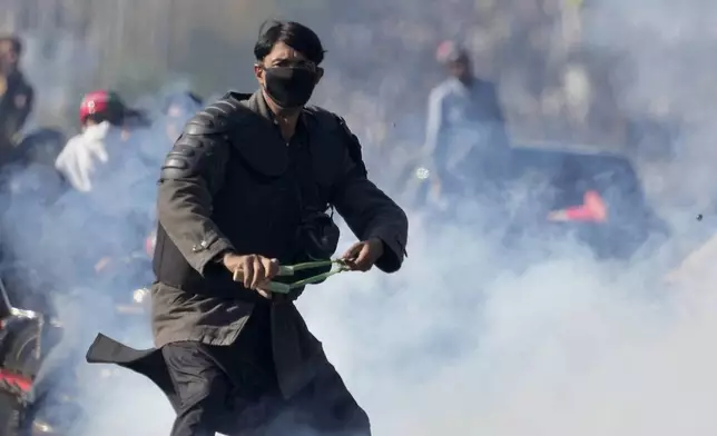 A supporters of imprisoned former premier Imran Khan's Pakistan Tehreek-e-Insaf party, aims to throw stones with slingshot following police fire tear gas shell to disperse them during clashes, in Islamabad, Pakistan, Tuesday, Nov. 26, 2024. (AP Photo/Anjum Naveed)