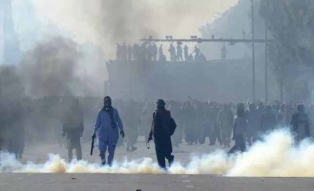 Supporters of imprisoned former premier Imran Khan's Pakistan Tehreek-e-Insaf party, throw stones after police officers fired tear gas shells to disperse them during clashes, in Islamabad, Pakistan, Tuesday, Nov. 26, 2024. (AP Photo/Irtisham Ahmed)
