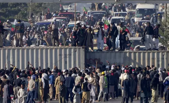 Supporters of imprisoned former premier Imran Khan's Pakistan Tehreek-e-Insaf party, remove shipping container to clear way for their rally demanding Khan's release, in Islamabad, Pakistan, Tuesday, Nov. 26, 2024. (AP Photo/Anjum Naveed)