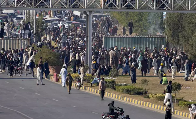 Supporters of imprisoned former premier Imran Khan's Pakistan Tehreek-e-Insaf party, gather to remove shipping container to clear way for their rally demanding Khan's release, in Islamabad, Pakistan, Tuesday, Nov. 26, 2024. (AP Photo/Anjum Naveed)