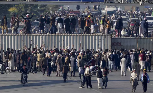 Supporters of imprisoned former premier Imran Khan's Pakistan Tehreek-e-Insaf party, gather to remove shipping containers to clear way for their rally demanding Khan's release, in Islamabad, Pakistan, Tuesday, Nov. 26, 2024. (AP Photo/Anjum Naveed)