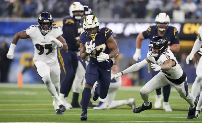 Los Angeles Chargers running back J.K. Dobbins (27) runs past Baltimore Ravens safety Kyle Hamilton (14) during the first half of an NFL football game Monday, Nov. 25, 2024, in Inglewood, Calif. (AP Photo/Eric Thayer)