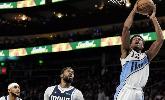 Atlanta Hawks forward De'Andre Hunter (12) shoots against Dallas Mavericks forward Naji Marshall, center, during the first half of an NBA basketball game, Monday, Nov. 25, 2024, in Atlanta. (AP Photo/Mike Stewart)