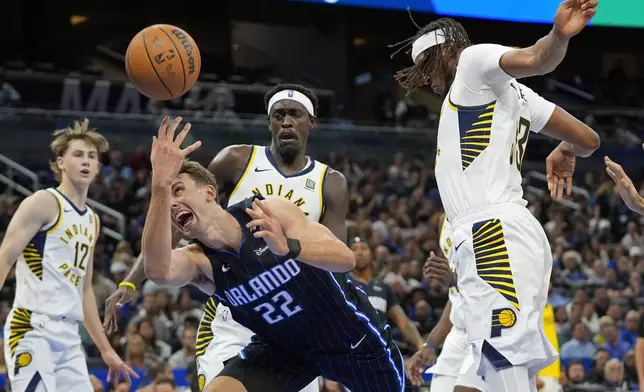 Orlando Magic forward Franz Wagner (22) loses control of the ball as he is fouled going between Indiana Pacers forward Pascal Siakam, back center, and center Myles Turner, right, during the first half of an NBA basketball game, Wednesday, Nov. 13, 2024, in Orlando, Fla. (AP Photo/John Raoux)