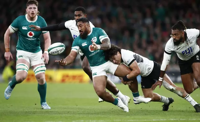 Ireland's Bundee Aki, centre, is tackled by Fiji's Caleb Muntz during the Autumn Nations Series rugby union match between Ireland and Fiji, at Aviva Stadium, Dublin, Ireland, Saturday, Nov. 23, 2024. (AP Photo/Peter Morrison)