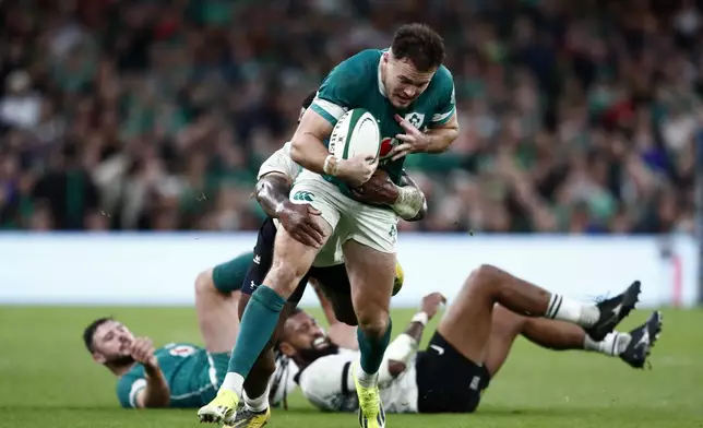 Ireland's Jacob Stockdale, front, is tackled by Fiji's Josua Tuisova during the Autumn Nations Series rugby union match between Ireland and Fiji, at Aviva Stadium, Dublin, Ireland, Saturday, Nov. 23, 2024. (AP Photo/Peter Morrison)