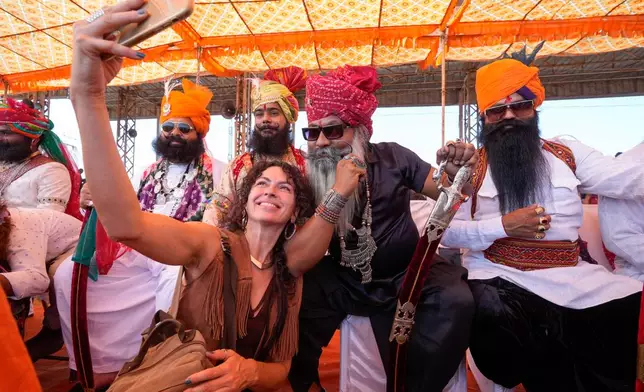 A tourist takes a selfie with a group of men participating in a moustache competition during a camel fair in Pushkar, in the northwestern Indian state of Rajasthan, Wednesday, Nov. 13, 2024. (AP Photo/Deepak Sharma)