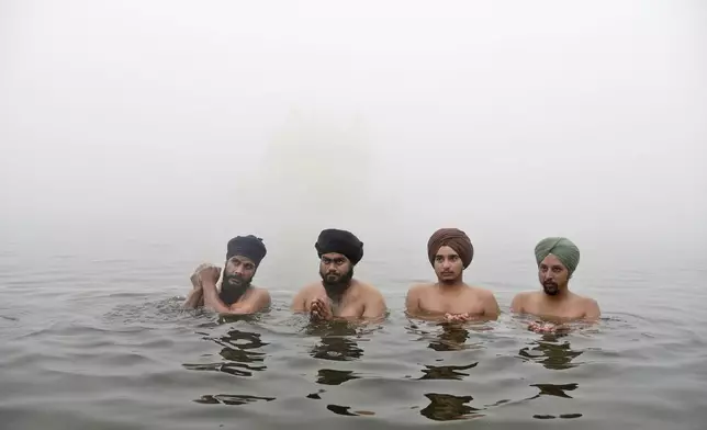 Sikh devotees pray while standing in the pond surrounding the Golden Temple as they celebrate the birth anniversary of the first Sikh guru, Guru Nanak, in Amritsar, India, Friday, Nov. 15, 2024. (AP Photo/Prabhjot Gill)