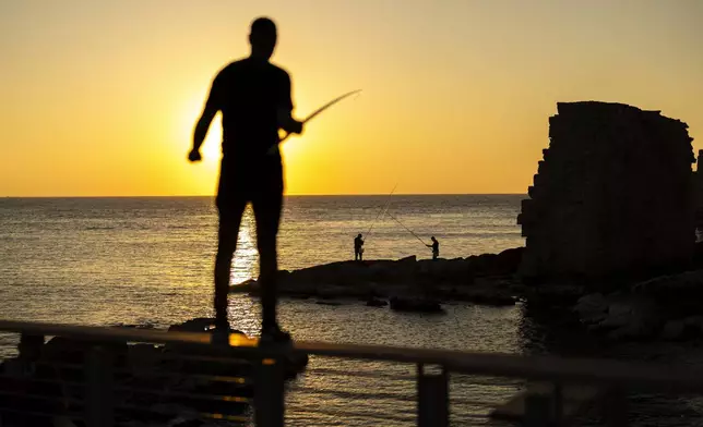 Fishermen throw their lines into the Mediterranean sea as the sun sets in the old city of Acre, Israel, on Friday, Nov. 15, 2024. (AP Photo/Francisco Seco)