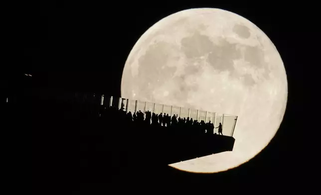 The moon rises behind an observation deck in New York City as seen from Hoboken, N.J., Friday, Nov. 15, 2024. (AP Photo/Seth Wenig)