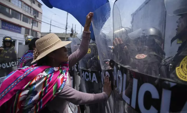 An anti-government protester pushes the shield of a police officer during a demonstration on the sidelines of the Asia-Pacific Economic Cooperation (APEC) summit in Lima, Peru, Friday, Nov. 15, 2024. (AP Photo/Guadalupe Pardo)