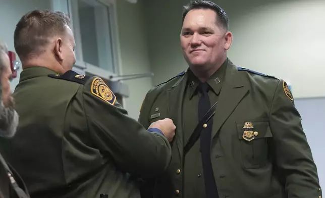 Border Patrol Agent Matthew A. Kiniery smiles as Chaplaincy program manager Spencer Hatch pins the chaplain pin on his uniform, Thursday, Nov. 21, 2024, in Dania Beach, Fla. (AP Photo/Marta Lavandier)