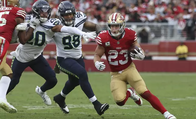 San Francisco 49ers running back Christian McCaffrey (23) runs against Seattle Seahawks safety Julian Love (20) and defensive tackle Roy Robertson-Harris (98) during the second half of an NFL football game in Santa Clara, Calif., Sunday, Nov. 17, 2024. (AP Photo/Jed Jacobsohn)