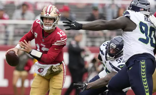 San Francisco 49ers quarterback Brock Purdy (13) is pressured by Seattle Seahawks defensive end Dre'Mont Jones (55) and defensive tackle Jarran Reed (90) during the first half of an NFL football game in Santa Clara, Calif., Sunday, Nov. 17, 2024. (AP Photo/Godofredo A. Vásquez)