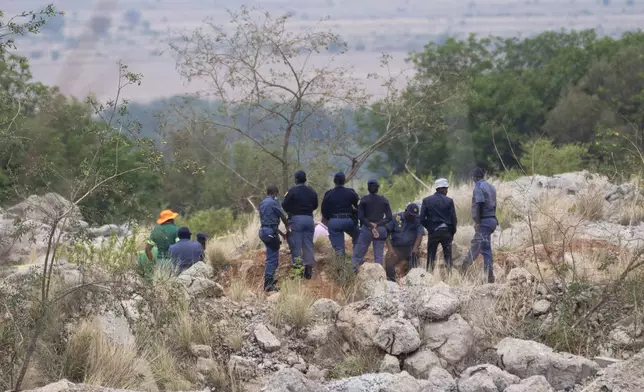 Rescue workers, left, remove a body from a reformed mineshaft where illegal miners are trapped inside a disused mine in Stilfontein, South Africa, Thursday, Nov.14, 2024. (AP Photo/Jerome Delay)