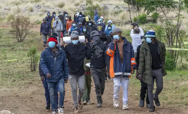 Volunteer rescue workers and community members leave a mine shaft where illegal miners are trapped in a disused mine in Stilfontein, South Africa, Thursday, Nov. 14, 2024. (AP Photo/Jerome Delay)