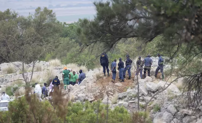 Rescue workers, bottom left, remove a body from a reformed mineshaft where illegal miners are trapped inside a disused mine in Stilfontein, South Africa, Thursday, Nov.14, 2024. (AP Photo/Jerome Delay)