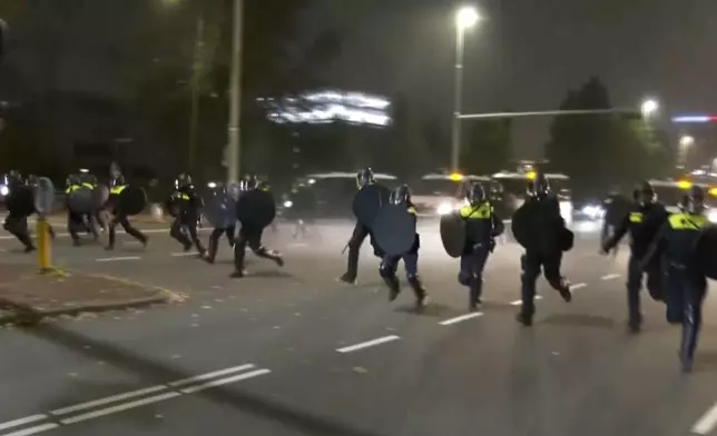 In this image taken from video, police in riot gear run towards protesters, after pro-Palestinian supporters marched near the soccer stadium, in Amsterdam, Netherlands, Thursday, Nov. 7, 2024. (RTL Nieuws via AP)