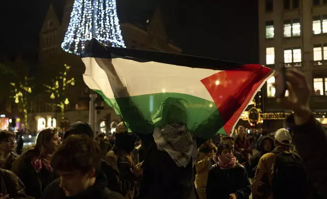 A pro-Palestinian protestor holds a Palestinian flag at a demonstration in Amsterdam, Netherlands, Wednesday, Nov. 13, 2024, despite a city ban on such gatherings. (AP Photo/Bram Janssen)