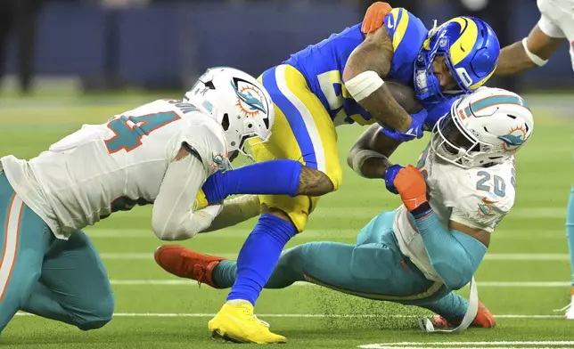 Los Angeles Rams running back Kyren Williams, center, is tackled by Miami Dolphins linebacker Chop Robinson, left, and linebacker Jordyn Brooks during the second half of an NFL football game, Monday, Nov. 11, 2024, in Inglewood, Calif. (AP Photo/Jayne Kamin-Oncea)