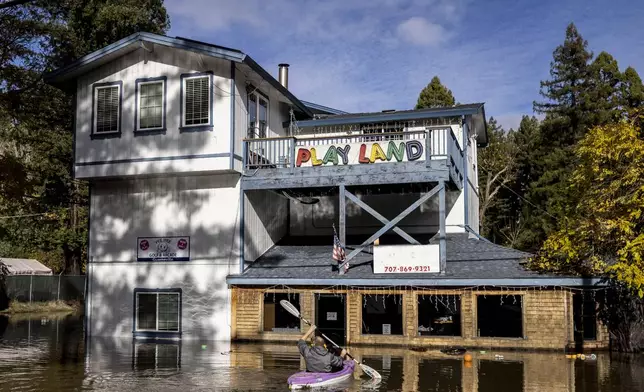 Tim Bosque, owner of Pee Wee Golf &amp; Arcade, kayaks in flood water to recover items that floated away after a major storm in Guerneville, Calif., Saturday, Nov. 23, 2024. (Stephen Lam/San Francisco Chronicle via AP)