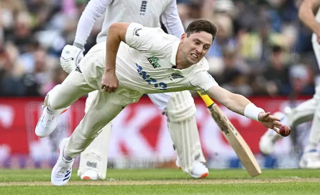 New Zealand's Matt Henry dives to field the ball during play on the second day of the first cricket test between England and New Zealand at Hagley Oval in Christchurch, New Zealand, Friday, Nov. 29, 2024. (Andrew Cornaga/Photosport via AP)