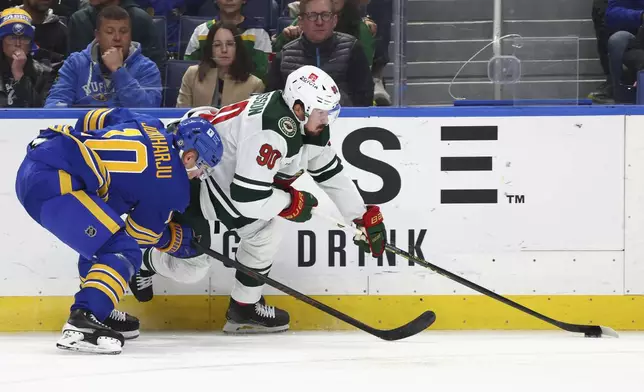 Minnesota Wild center Marcus Johansson (90) is checked by Buffalo Sabres defenseman Henri Jokiharju (10) during the second period of an NHL hockey game Wednesday, Nov. 27, 2024, in Buffalo, N.Y. (AP Photo/Jeffrey T. Barnes)