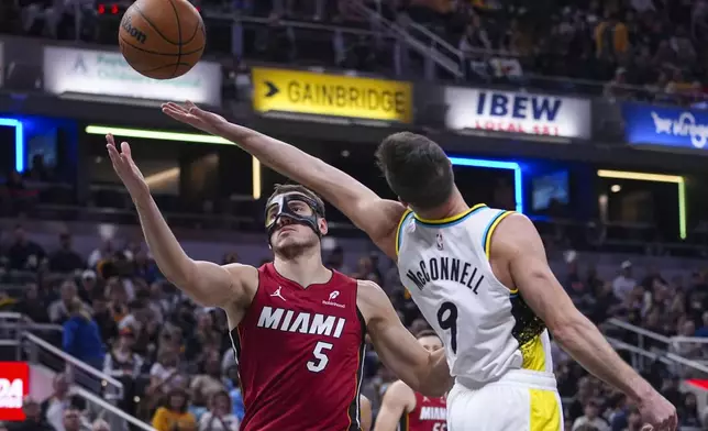 Indiana Pacers guard T.J. McConnell (9) tips the ball away from Miami Heat forward Nikola Jovic (5) during the first half of an NBA basketball game in Indianapolis, Sunday, Nov. 17, 2024. (AP Photo/Michael Conroy)