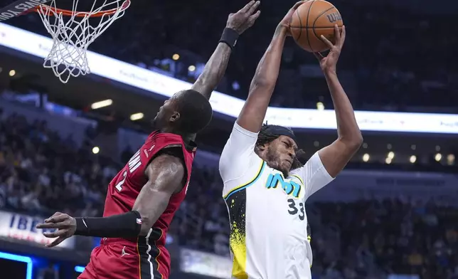 Indiana Pacers center Myles Turner (33) grabs a rebound behind Miami Heat guard Terry Rozier (2) during the first half of an NBA basketball game in Indianapolis, Sunday, Nov. 17, 2024. (AP Photo/Michael Conroy)