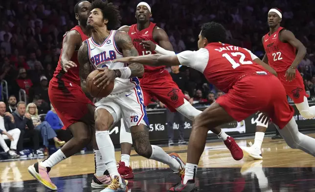 Philadelphia 76ers guard Kelly Oubre Jr., center, goes to the basket as Miami Heat guard Dru Smith (12) defends during the first half of an NBA basketball game, Monday, Nov. 18, 2024, in Miami. (AP Photo/Lynne Sladky)