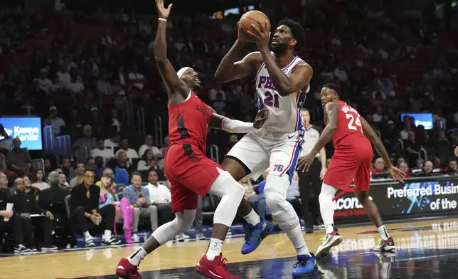 Philadelphia 76ers center Joel Embiid (21) goes to the basket as Miami Heat center Bam Adebayo, left, defends during the first half of an NBA basketball game, Monday, Nov. 18, 2024, in Miami. (AP Photo/Lynne Sladky)