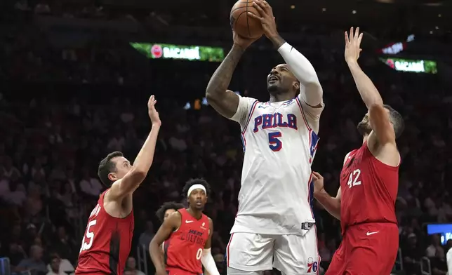 Philadelphia 76ers center Andre Drummond (5) goes to the basket as Miami Heat forwards Duncan Robinson (55) and Kevin Love (42) defend during the first half of an NBA basketball game, Monday, Nov. 18, 2024, in Miami. (AP Photo/Lynne Sladky)