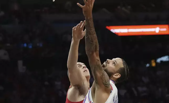 Philadelphia 76ers forward Caleb Martin, right, goes to the basket as Miami Heat guard Tyler Herro, left, defends during the first half of an NBA basketball game, Monday, Nov. 18, 2024, in Miami. (AP Photo/Lynne Sladky)