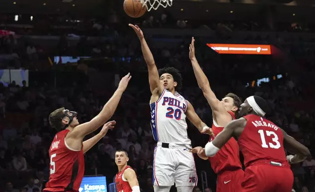 Philadelphia 76ers guard Jared McCain (20) goes to the basket over Miami Heat forward Nikola Jovic (5) during the first half of an NBA basketball game, Monday, Nov. 18, 2024, in Miami. (AP Photo/Lynne Sladky)